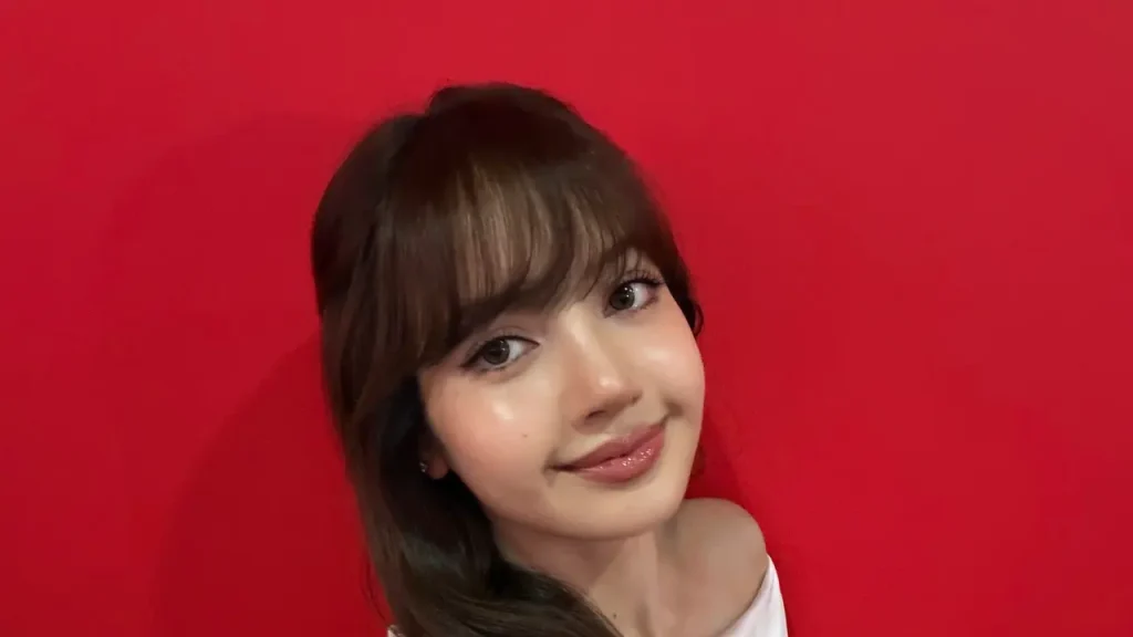 Lisa BLACKPINK tampil glowing di acara Shiseido Bangkok mengenakan gaun merah elegan dengan makeup natural dan kulit bercahaya.