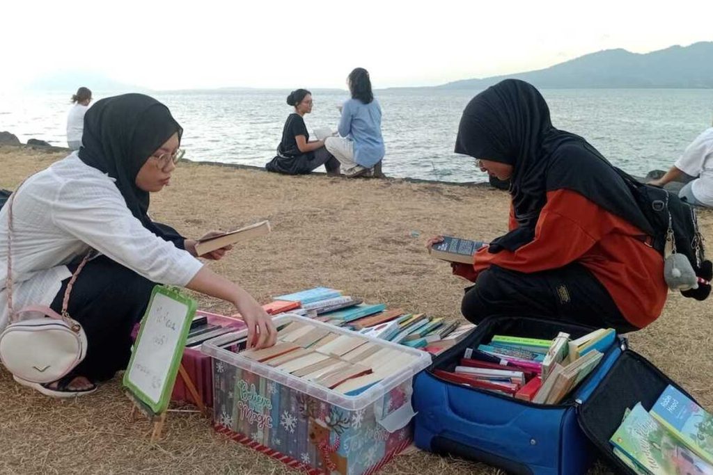 Suasana pengunjung membaca buku di lapak baca gratis Komunitas Lembar Senja di kawasan Megamas, Kota Manado.